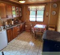A kitchen in a family house with wooden cabinets and a traditional stove, dining area.