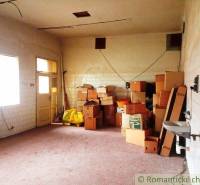 Interior of a family house with stored boxes and a sink, white tiles on the walls.