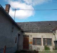 A family house with wooden windows, doors, and a shingle roof in the countryside.