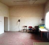A spacious room with tiles on the walls, old chairs, heating, and natural lighting.