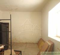An empty room with a window, a shelf, and building materials in a family house.
