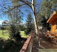 A wooden house with a terrace in the middle of the forest, offering a beautiful view of the landscape.