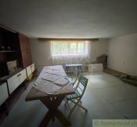 Dining room in a family house with simple furniture and wooden paneling.