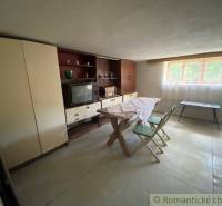 Retro living room with wooden furniture, television, and folding chairs in a family house.