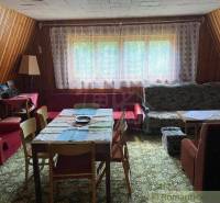 A living room with antique furniture, wooden walls, and a patterned carpet in a family house.