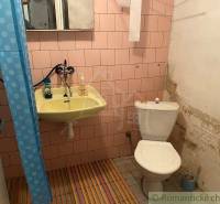 A bathroom with pink tiles, a sink, and a toilet, suitable for a family house.