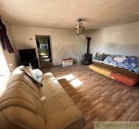 Living room in a family house with a sofa and a fireplace, next to a duvet on the bed.