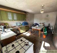 A kitchen with a gas stove, green cabinets, and a table in a family house.