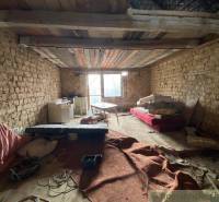 An abandoned room with old furniture and earthy walls in a family house.
