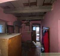 A room with old furniture in a family house with hanging clothes and unfinished walls.