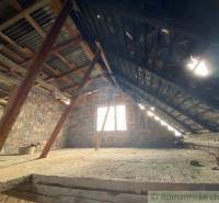 Attic with a sloped metal roof and brick walls in a family house.