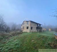 A stone family house in the countryside, surrounded by mist and trees, with a spacious plot.