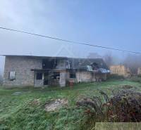 An old family house in the countryside surrounded by grass and a misty landscape.