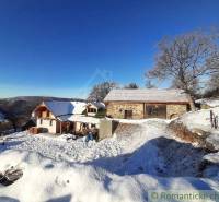 Snow on a picturesque family house and cottage in a winter landscape with a blue sky.