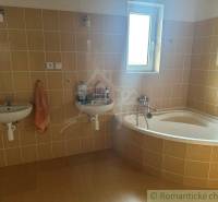 Bathroom in a family house with a corner bathtub, sinks, and toiletries.