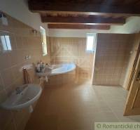 Bathroom with a bathtub and two sinks, tiles, wooden ceilings in a family house.