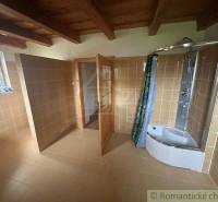 A bathroom with an almost empty space, a wooden ceiling, a shower, and a window in a family house.