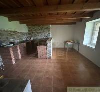 In the interior, we see the kitchen of a family house with brick cladding and a wooden ceiling.