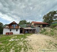 A family house with wooden cladding in a natural setting on a gentle hill.