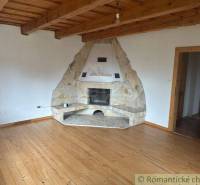 Wooden ceiling with a fireplace and light flooring in a cozy family house.