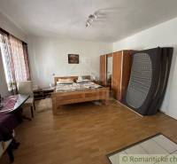 A bedroom with a parquet floor contains a double bed, wardrobes, and a desk. Family house.