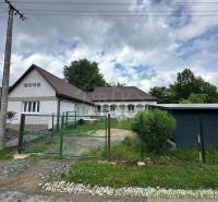 A family house with a large garden and a garage surrounded by nature.