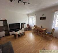 Living room in a family house with a television, sofa set, dining table, wooden floor.