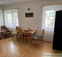 Dining room in a family house with furniture and windows with curtains, a comfortable chair, and flooring.