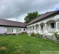 A family house with a white facade, arched arcade, and satellite, surrounded by a lawn.