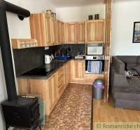 A kitchen in a wooden style and a family house with a sofa and a tiled stove.