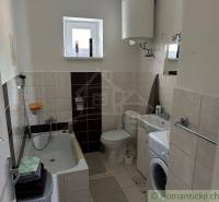 Compact bathroom in a family house with a bathtub, washing machine, and water heater.