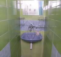 A narrow space with a sink and green tiles suitable for a family house.