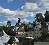 A historic town with church towers, green trees, and a blue sky with clouds.