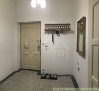 Hallway in a 2-room apartment with coat hooks, a mirror, and wooden doors.