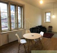 Dining nook with a window and a 2-room apartment; wooden floor, round table, chairs.