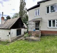 A family house in Nová Baňa with an extension, lawn, and trees in the background.