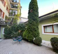 An outdoor space on Nitrianska Street with offices, chairs, and trees surrounded by greenery.