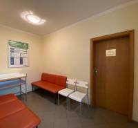 Waiting room with red seats on Nitrianska street, entrance to the office, information board.