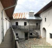Stone courtyard with wooden railing, metal roof, peculiar properties.