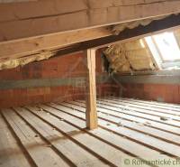 Attic with wooden beams, brick wall, and skylight, ideal for unique properties.