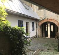 A cozy courtyard with historic architecture of unique properties, surrounded by plants and stones.