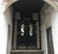 A stone pavement leads to historic wooden doors, surrounded by a brick arch.