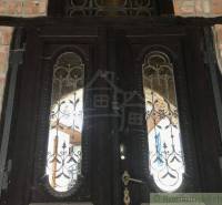 Wooden door with decorative metal inlay, surrounded by a brick wall.