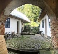 A stone courtyard with a rustic atmosphere complemented by wooden furniture and unique properties.