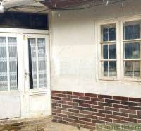 Old wooden door and window; traditional cottage with a brick plinth.