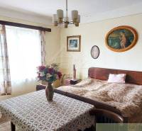 A room in a cottage with retro furniture, a rustic atmosphere, curtains, paintings, flowers.