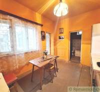 A kitchen in a family house, curtains, a table, chairs, a door leading to the toilet.