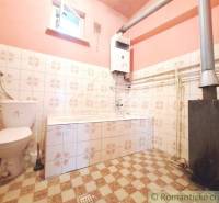A bathroom with tiles and a stove, part of a family house with rustic charm.
