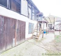An older family house with wooden doors, an exterior staircase, and courtyards, awaiting renovation.