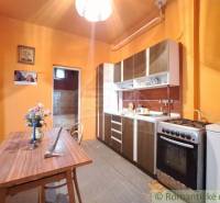 Kitchen with a wooden table, stove, family house; decorations and orange walls.